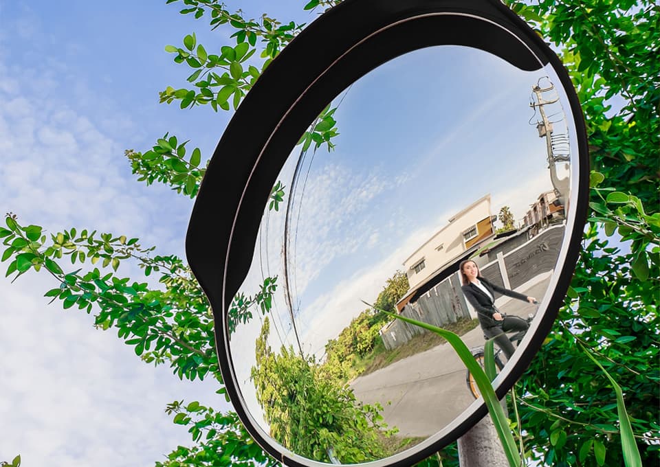 Miroir de surveillance rond convexe sur mât, installé en extérieur pour dégager la visibilité d'une sortie de voie.